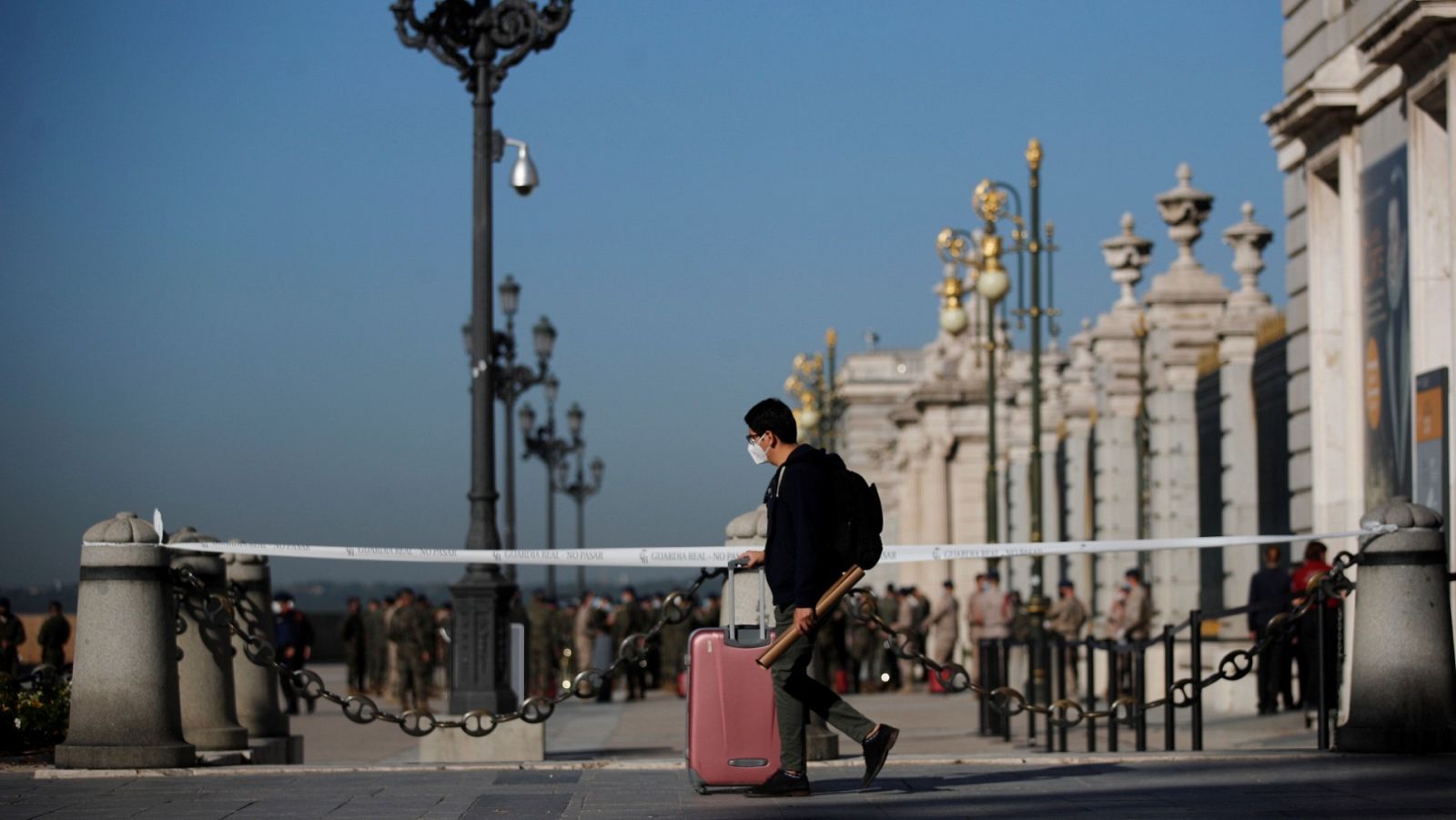 Un joven con su maleta pasa ante el Palacio Real de Madrid, este viernes.