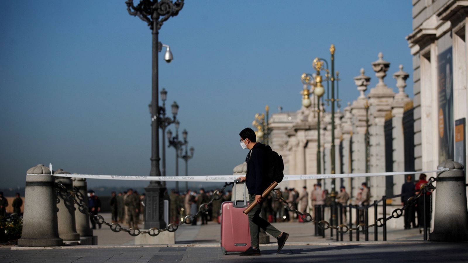 Un joven con su maleta pasa ante el Palacio Real de Madrid