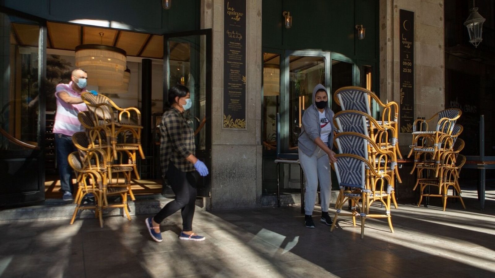 Dos trabajadores recogen la terraza de un bar del centro de Barcelona