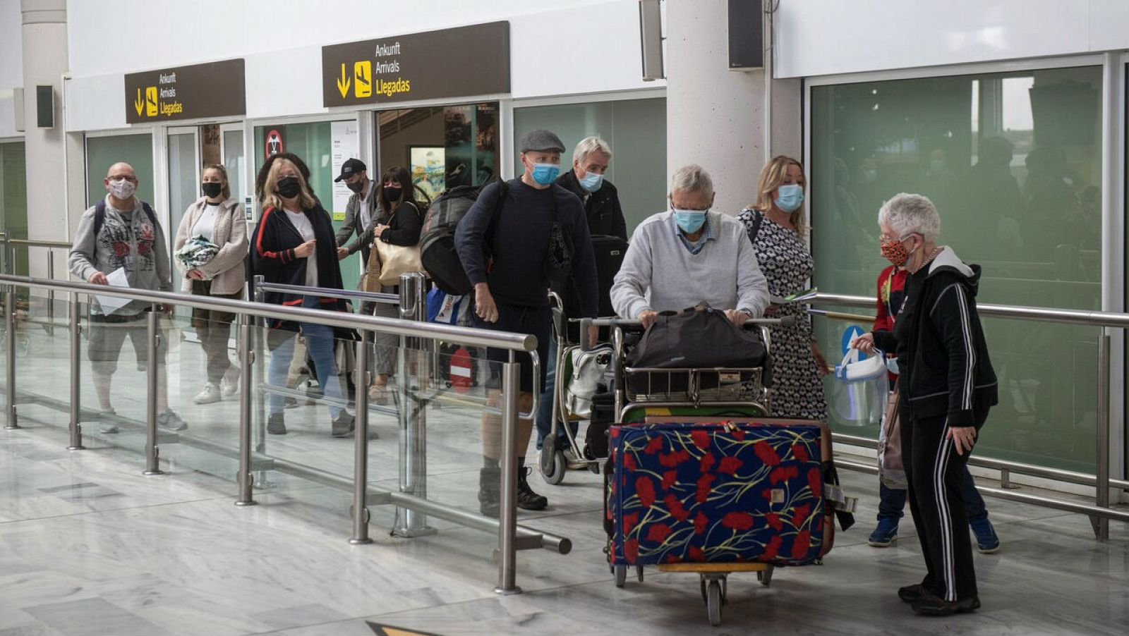 Varios turistas salen de la sala de recogida de equipajes a su llegada al aeropuerto César Manrique de Lanzarote, Canarias.