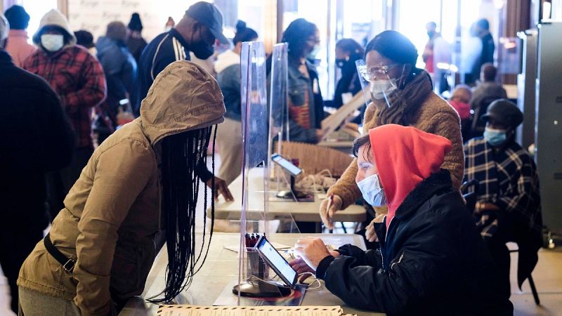 Un voluntario de un centro de votación registra a una votante para las elecciones presidenciales de EE.UU.