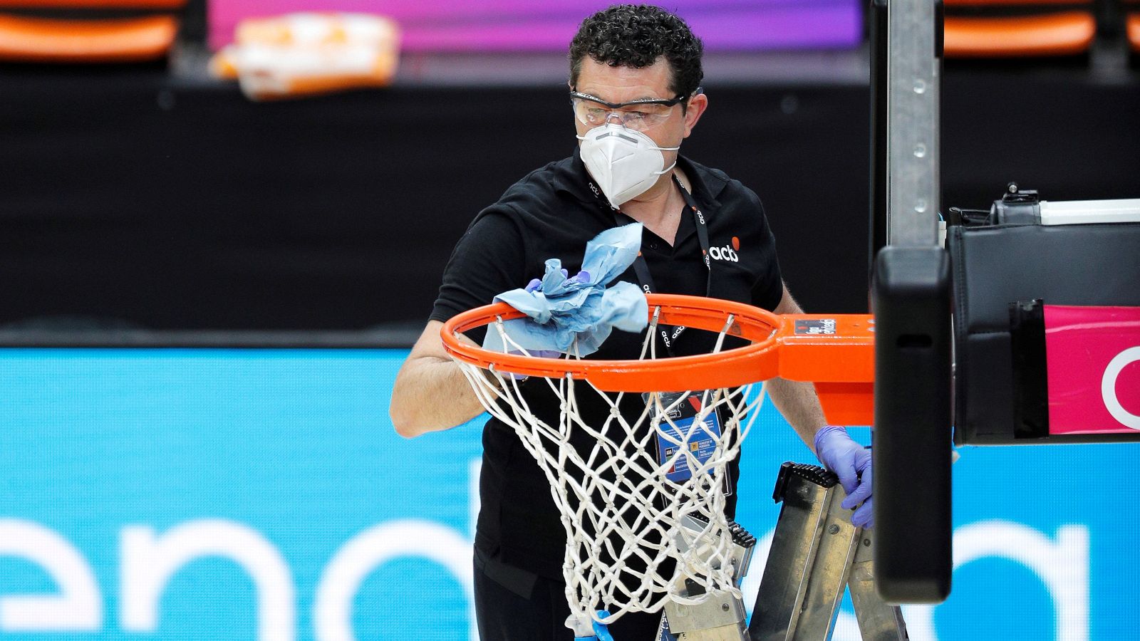 Un operario desinfecta uno de los aros para un partido de la Liga ACB