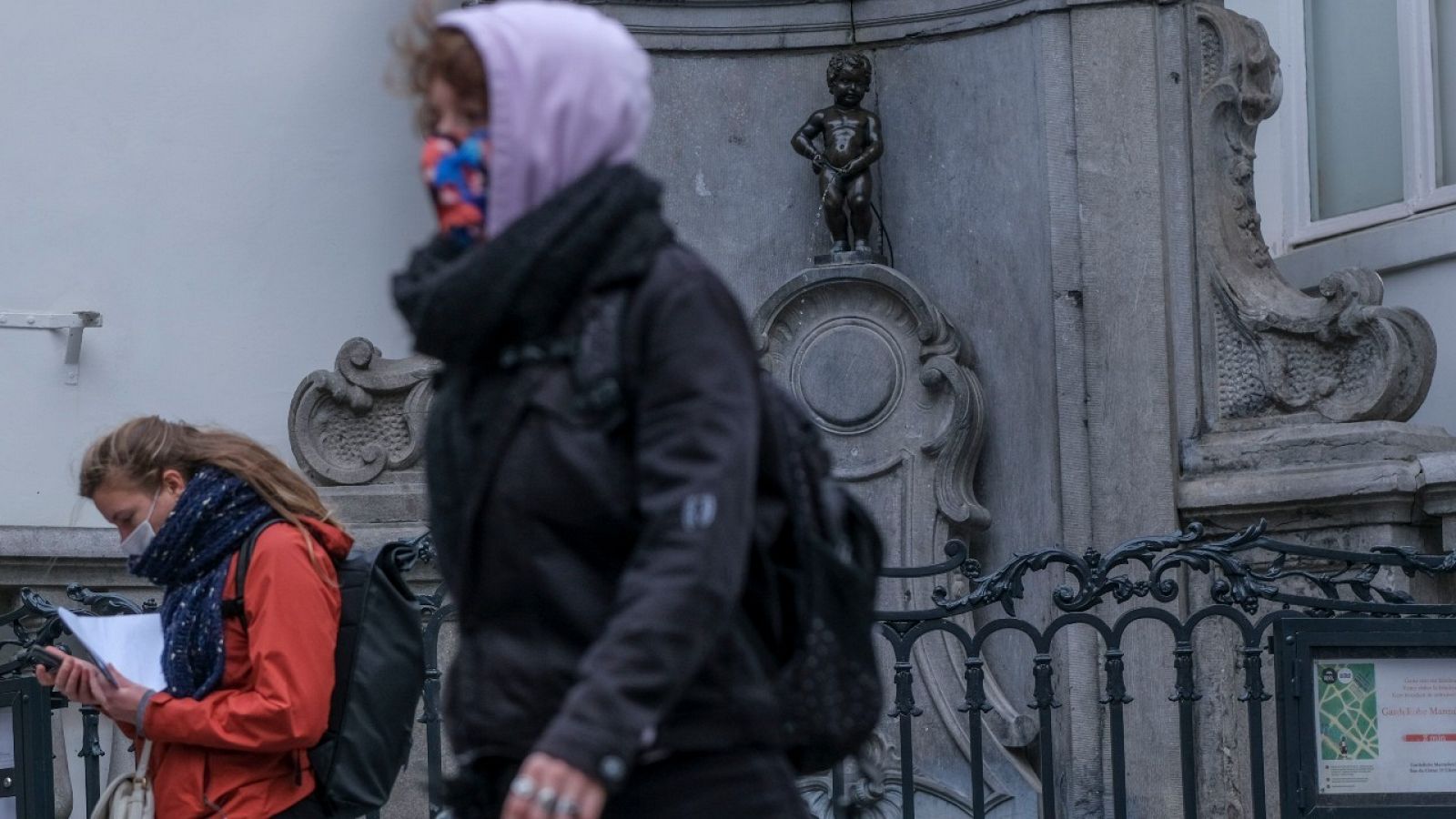 Gente con mascarilla delante de la estatua del Manneken Pis en el centro histórico de Bruselas, Bélgica.