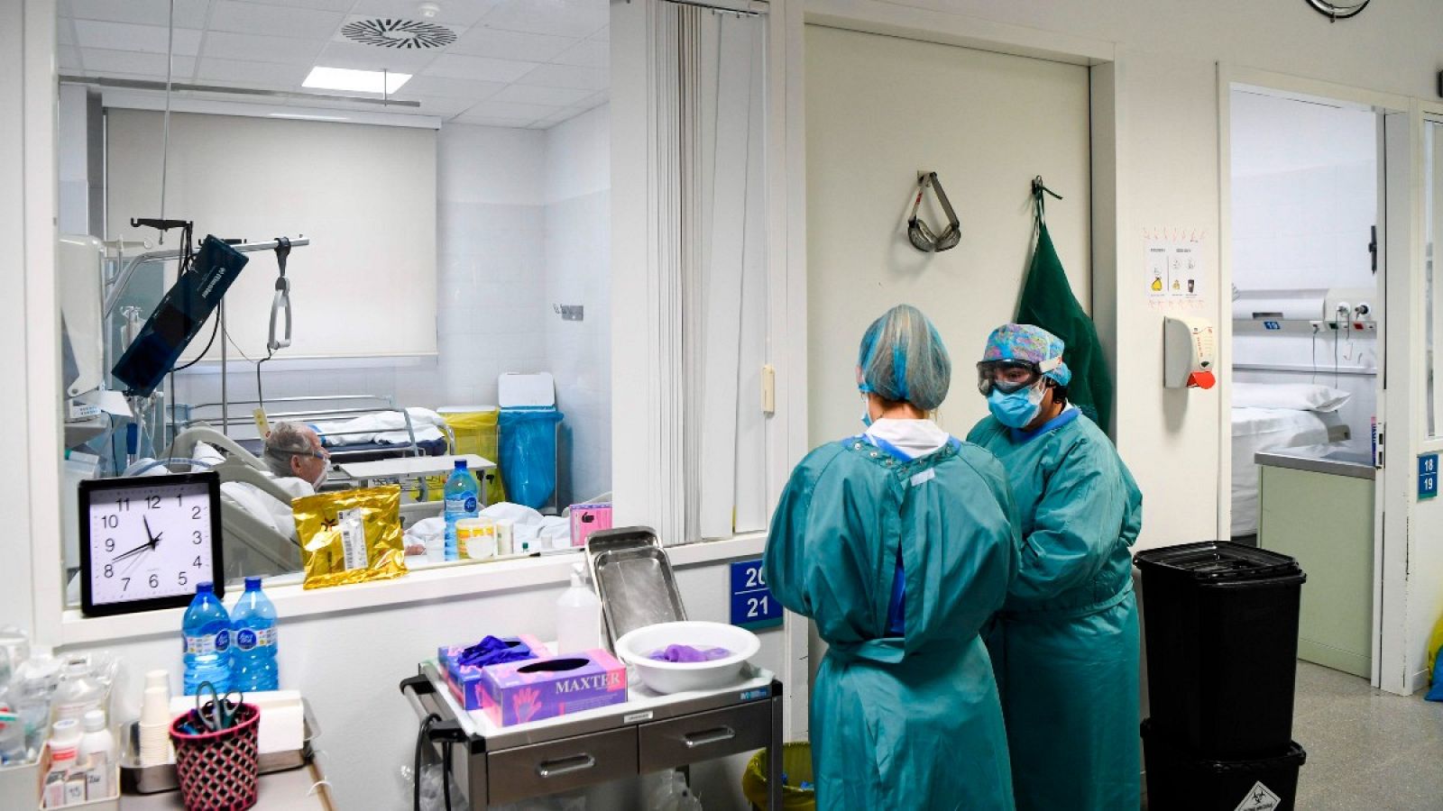 Dos sanitarias se preparan para entrar en la habitación de un paciente