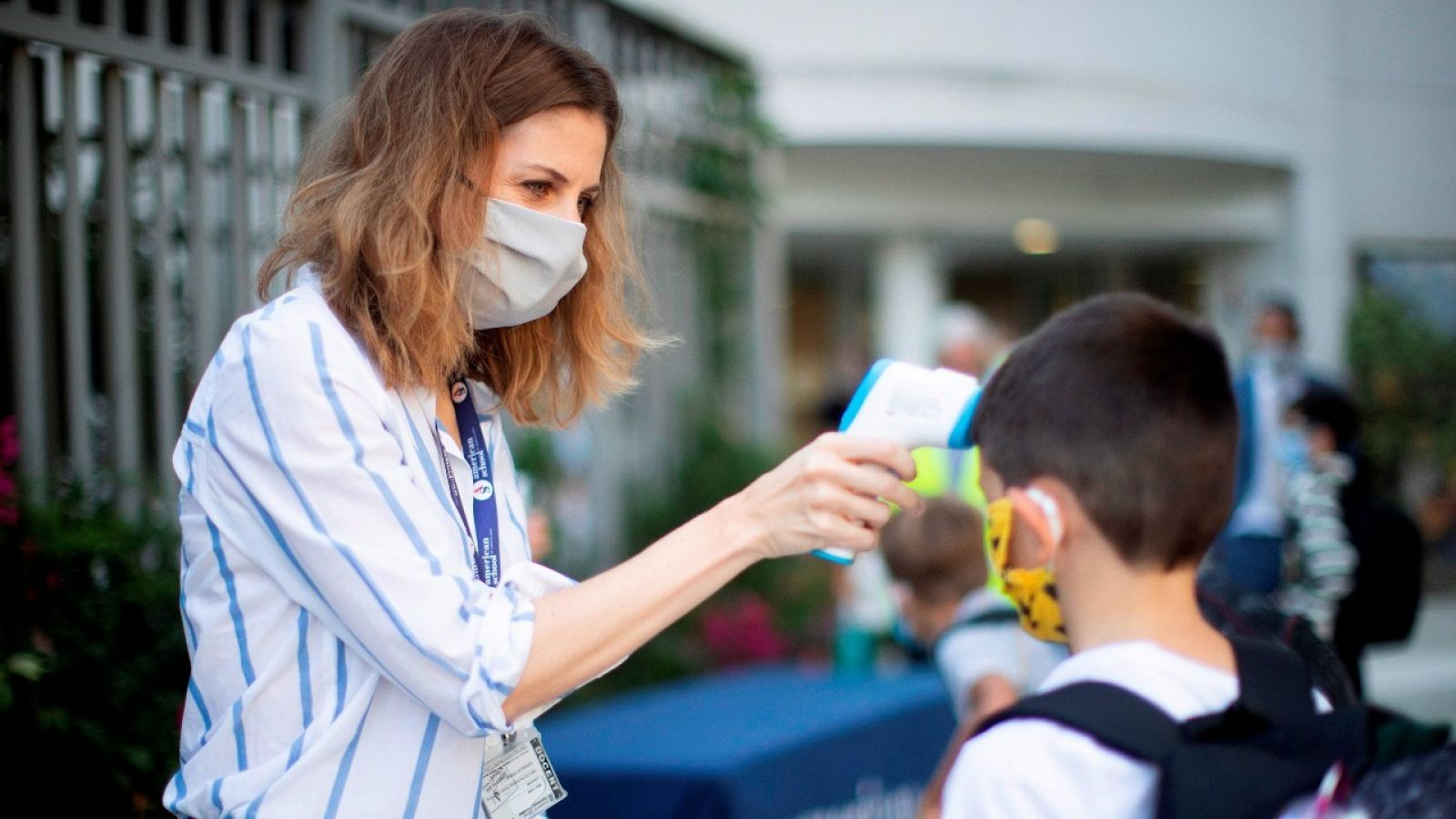 Una trabajadora toma la temperatura a un niño a la entrada del colegio.