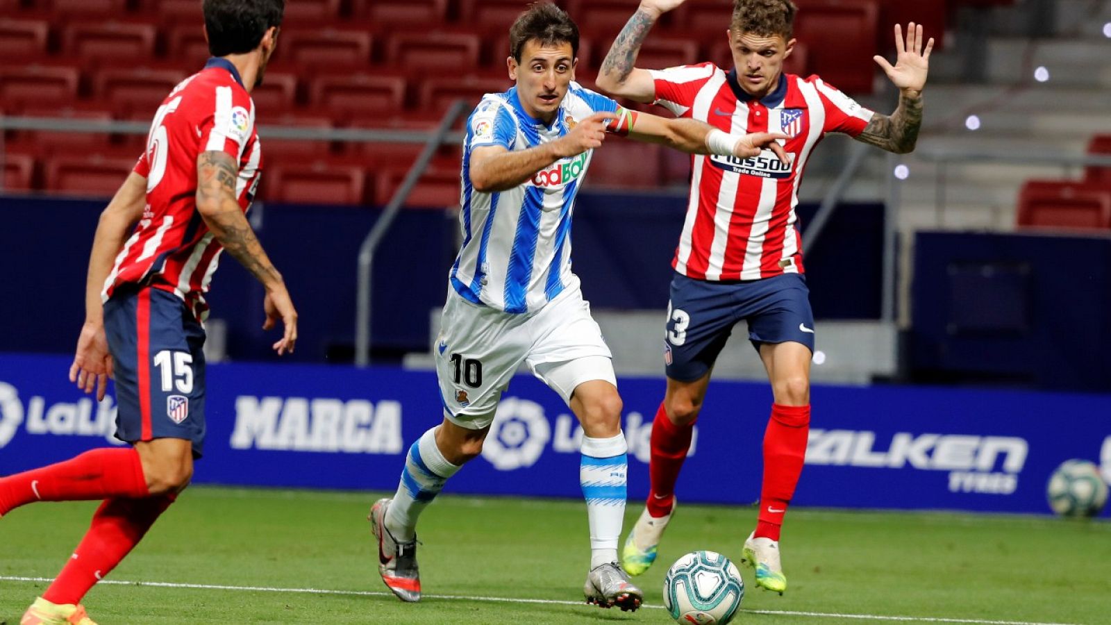 El lateral derecho del Atlético de Madrid Kieran Trippier (d) lucha por el balón con el jugador de la Real Sociedad, Mikel Oyarzabal (c).