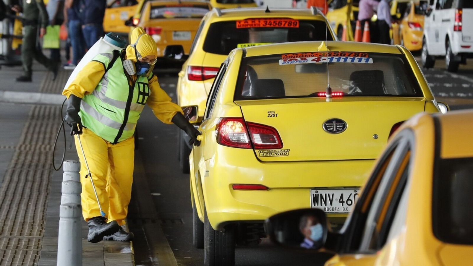 Una mujer desinfecta los taxis en Bogotá, Colombia