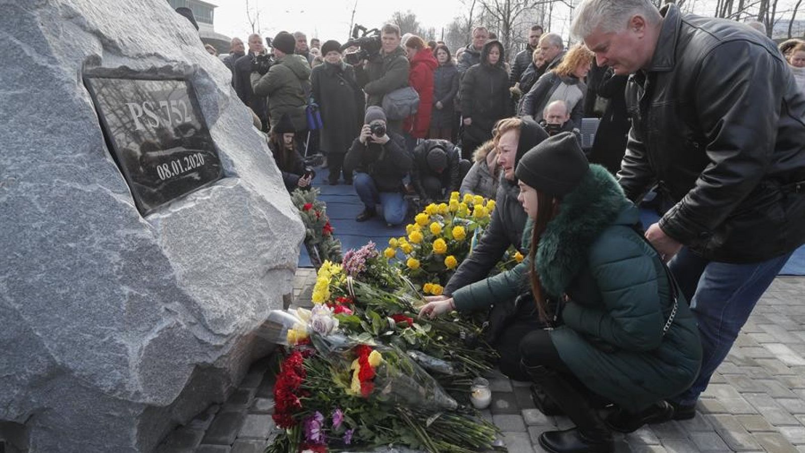 Parientes y amigos de las víctimas colocan flores en una piedra conmemorativa