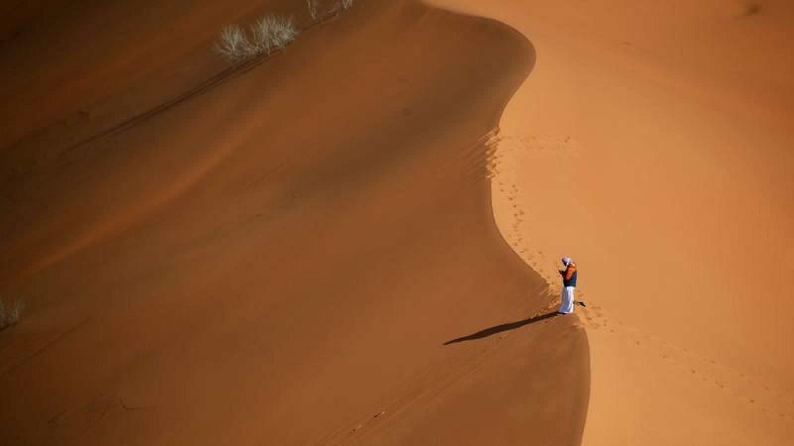Un hombre permanece en lo alto de una duna durante la sexta etapa del Dakar 2021. 