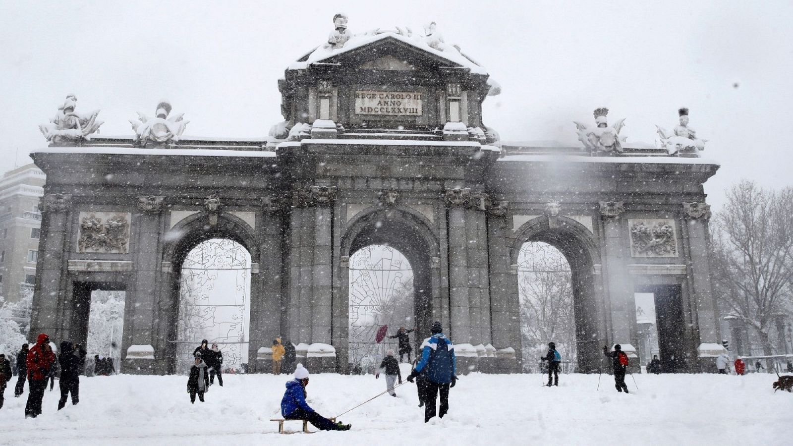 Varias personas caminan junto a la Puerta de Alcalá de Madrid, este sábado.