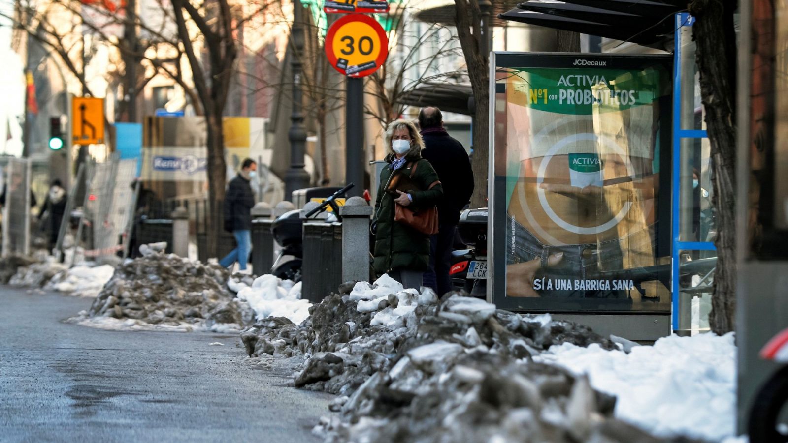 Una mujer espera el autobús en una parada de Madrid entre las acumulaciones de nieve diez días después del temporal Filomena