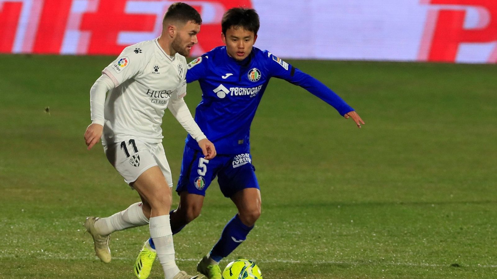 El extremo japonés del Getafe Take Kubo (d) disputa un balón ante el centrocampista del Huesca Javi Galán (i)