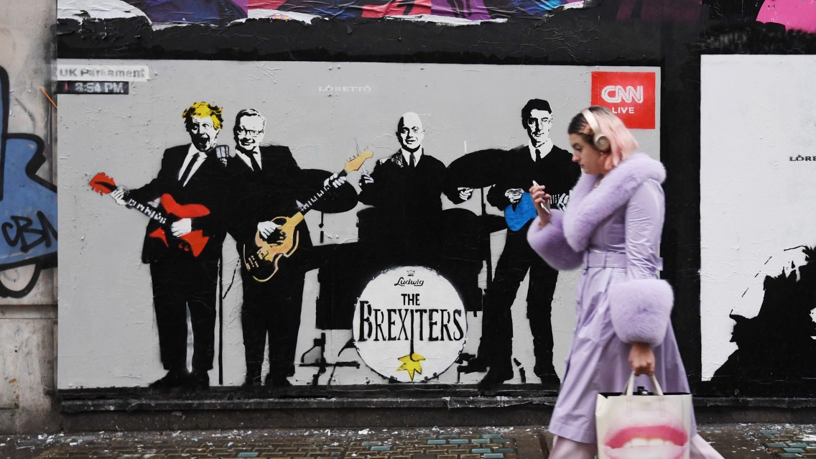 Una mujer camina frente a una obra de arte callejero del artista 'Loretto' en Londres, Reino Unido.