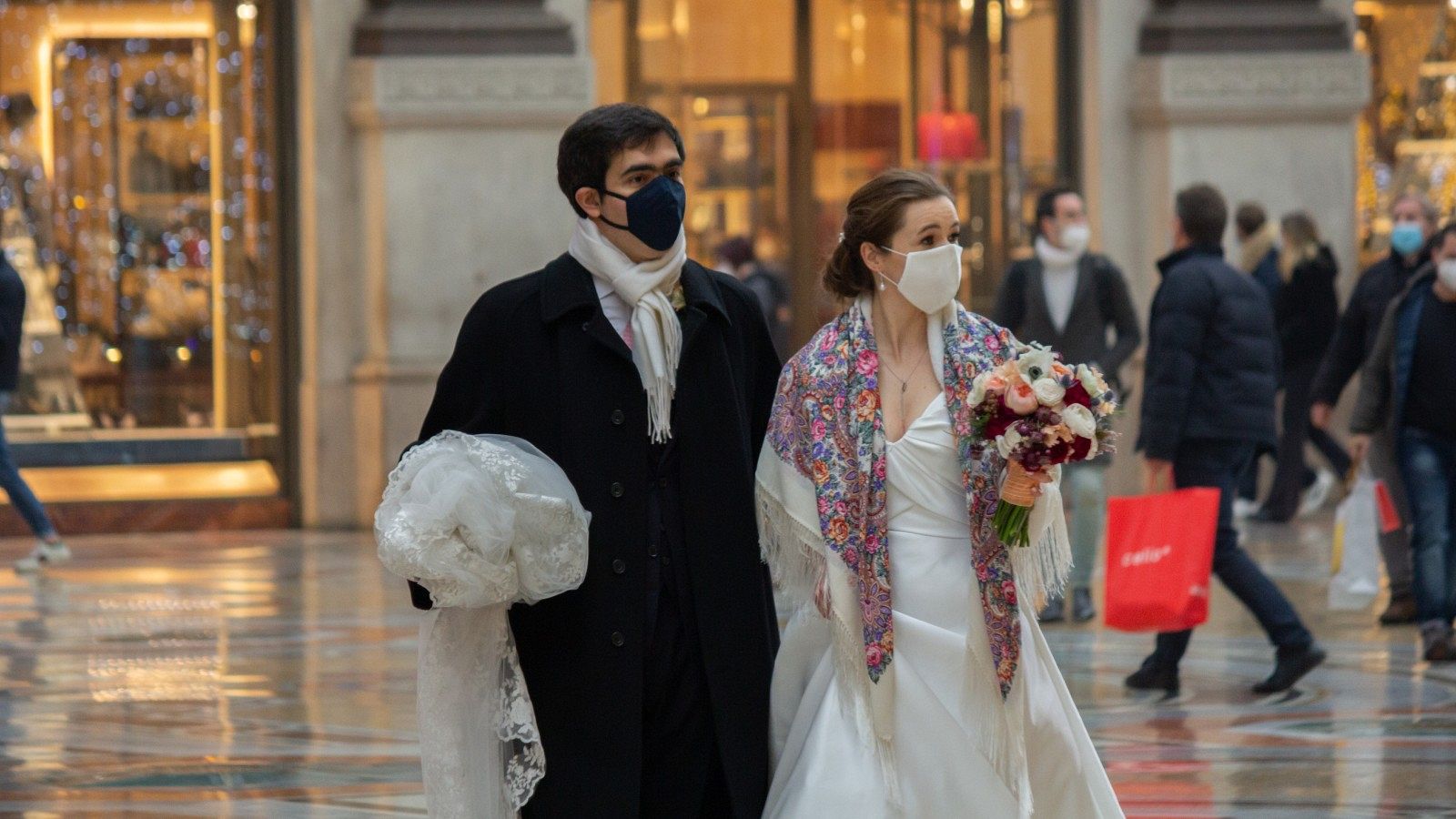 Una pareja, recién casada, pasea con mascarillas en la Galeria Vittorio Emanuele de Milán.