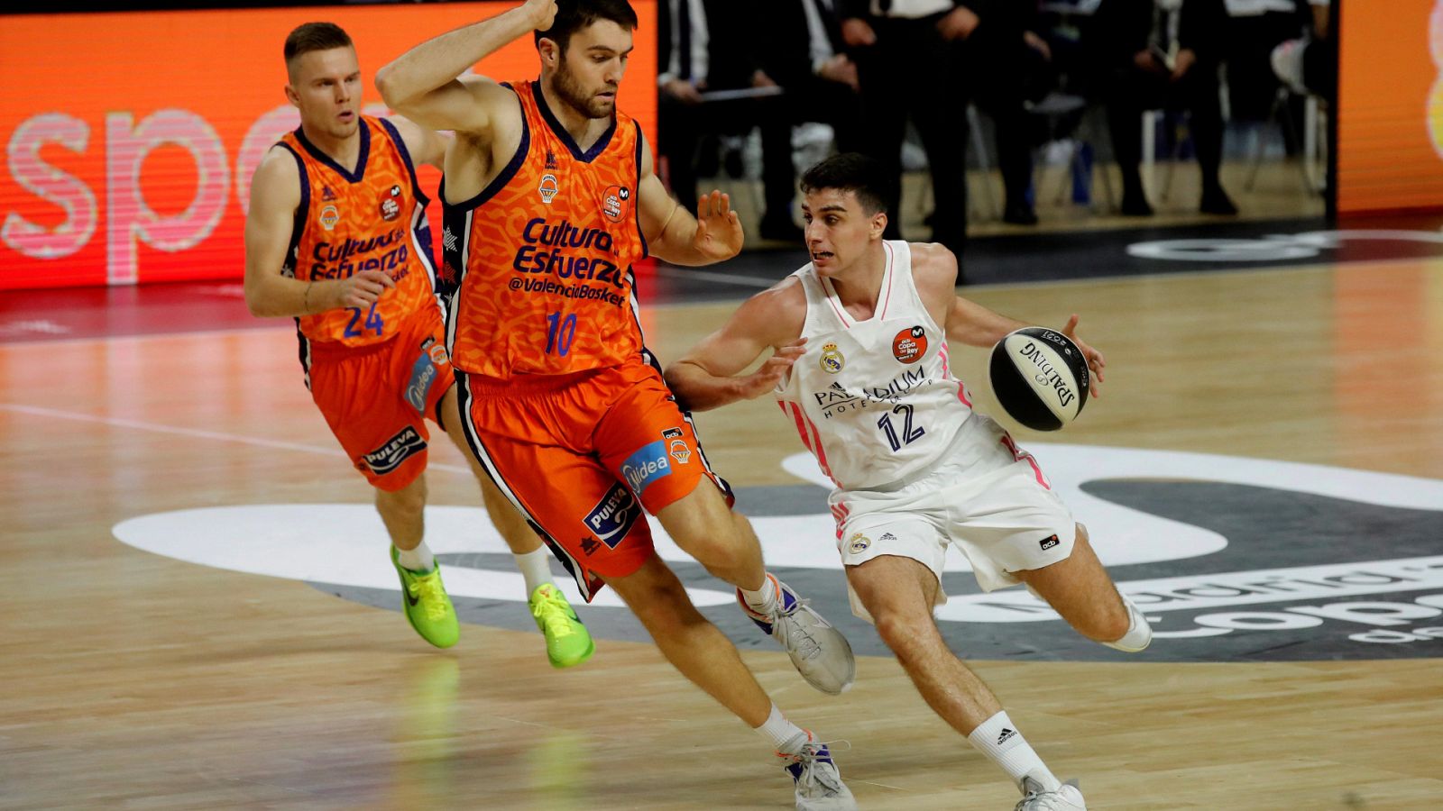El base español del Real Madrid, Carlos Alocén (d), maneja el balón ante la oposición de Mike Tobey (c), pívot estadounidense del Valencia Basket.