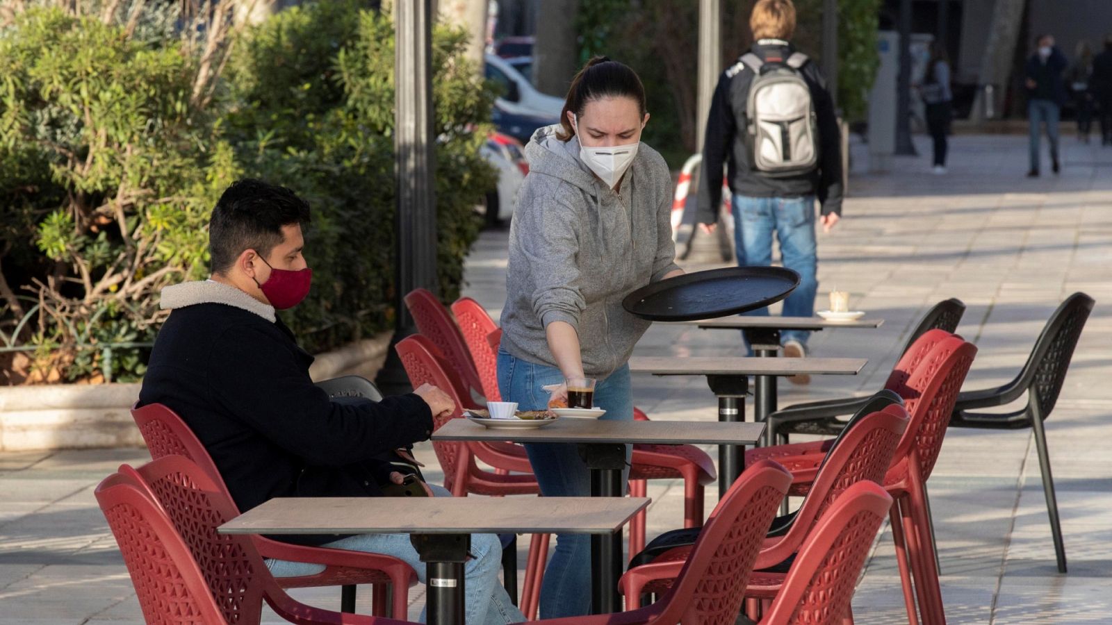 Una camarera de una cafetería sirve un café a un cliente