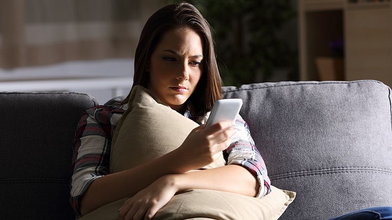 Una joven mira la pantalla de su teléfono móvil.