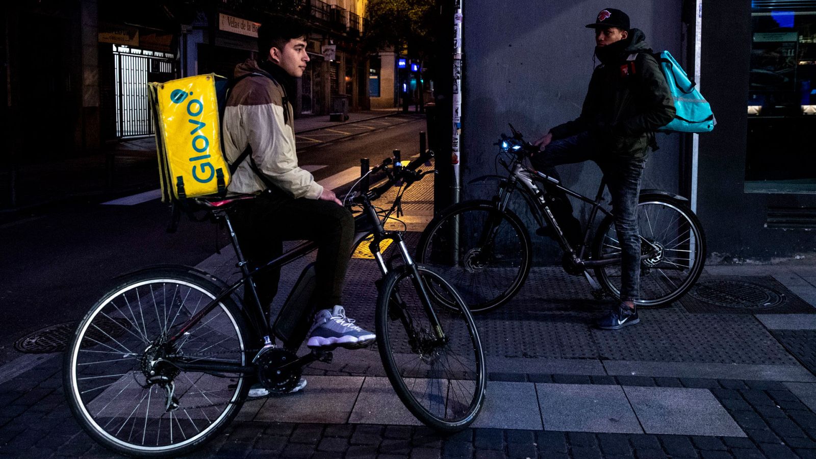  Dos riders esperan un pedido fuera de una comercio en Madrid