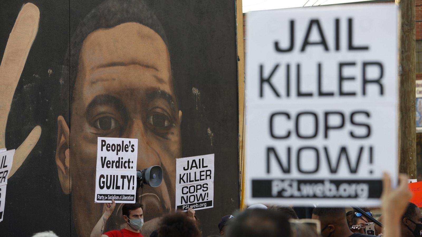 Un grupo de personas cerca de un mural de George Floyd en Minneapolis.