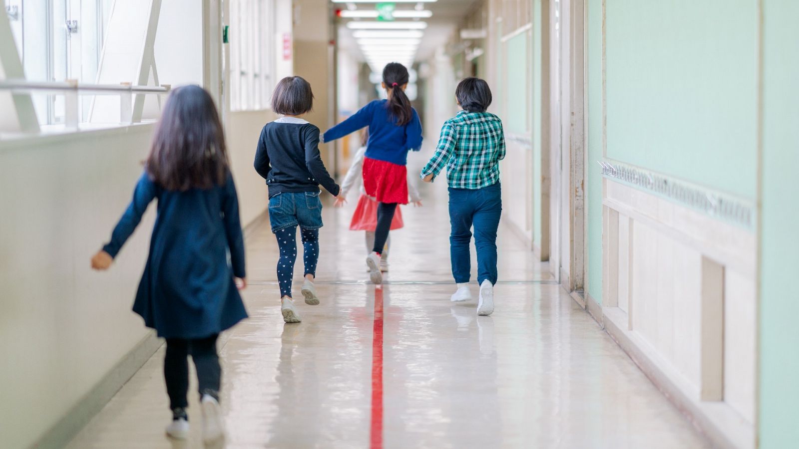 Un grupo de niños camina por el pasillo de un colegio.