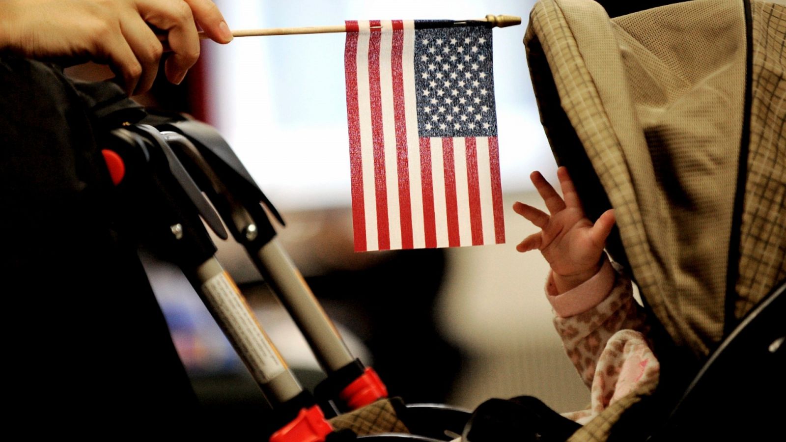 Imagen de archivo de un bebé intentando tocar la bandera de Estados Unidos que sostiene su madre durante un acto en Nueva York.