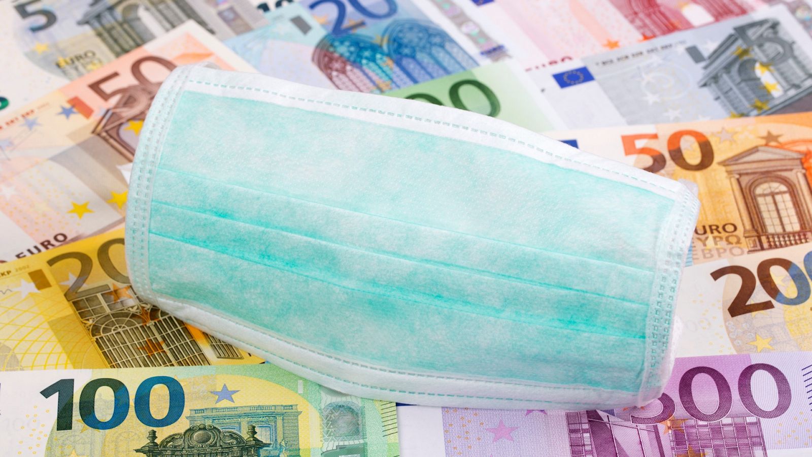Una mascarilla sobre un fondo de billetes de euro