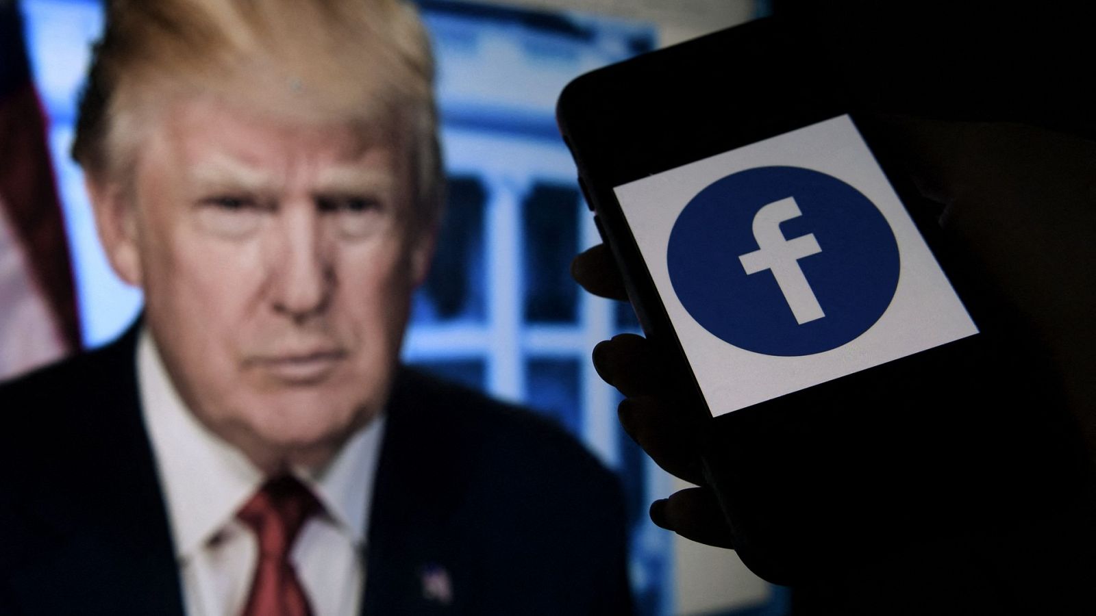 La pantalla de un teléfono muestra un logotipo de Facebook con el retrato oficial del ex presidente de los Estados Unidos, Donald Trump