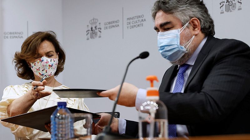 Carmen Calvo y José Manuel Rodríguez Uribes intercambian documentos durante la firma de un Convenio para digitalizar fondos documentales de interés para la Memoria Democrática