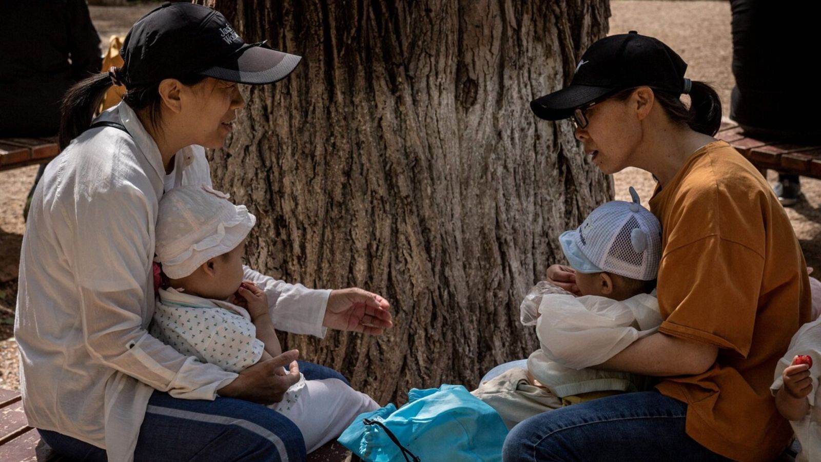 Imagen de archivo de dos mujeres con sus niños en Pekín. Foto: NICOLAS ASFOURI / AFP