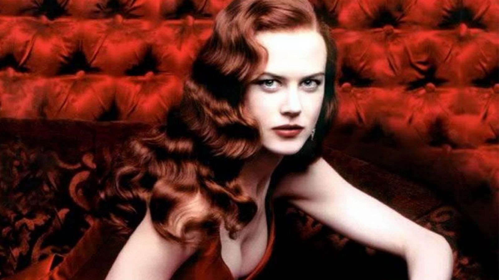 Nicole Kidman en la película 'Moulin Rouge', pelirroja y vestida de rojo sobre un sofá del mismo color