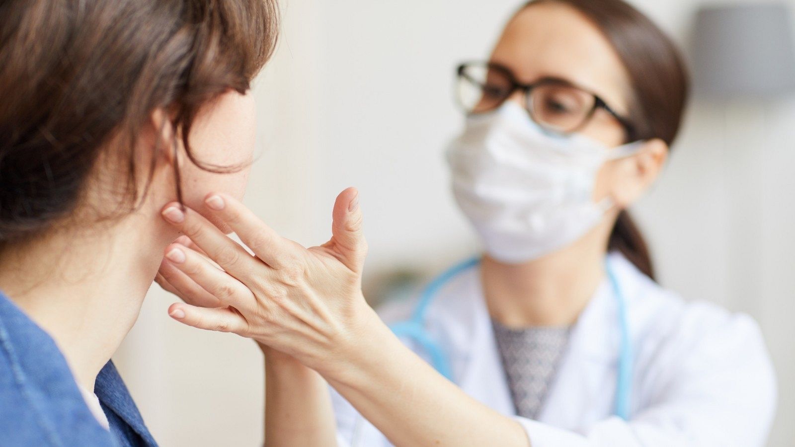 Una doctora con mascarilla atiende a una paciente.