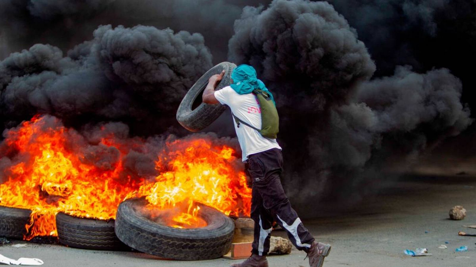 Un hombre arroja una llanta a una barricada en llamas durante una jornada de protestas, en Cap-Haitien (Haití). 