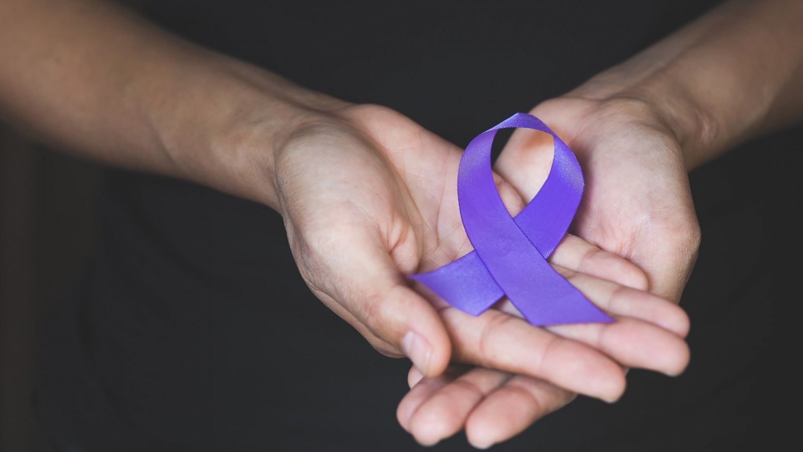 Una mujer con un lazo morado, símbolo de la lucha contra la violencia de género