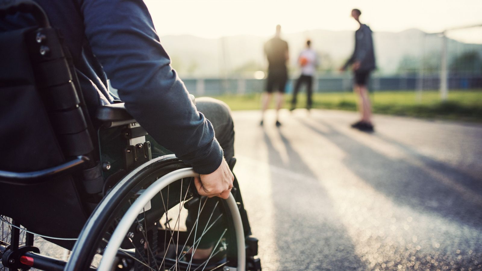Una persona con discapacidad física se desplaza en silla de ruedas por la calle.