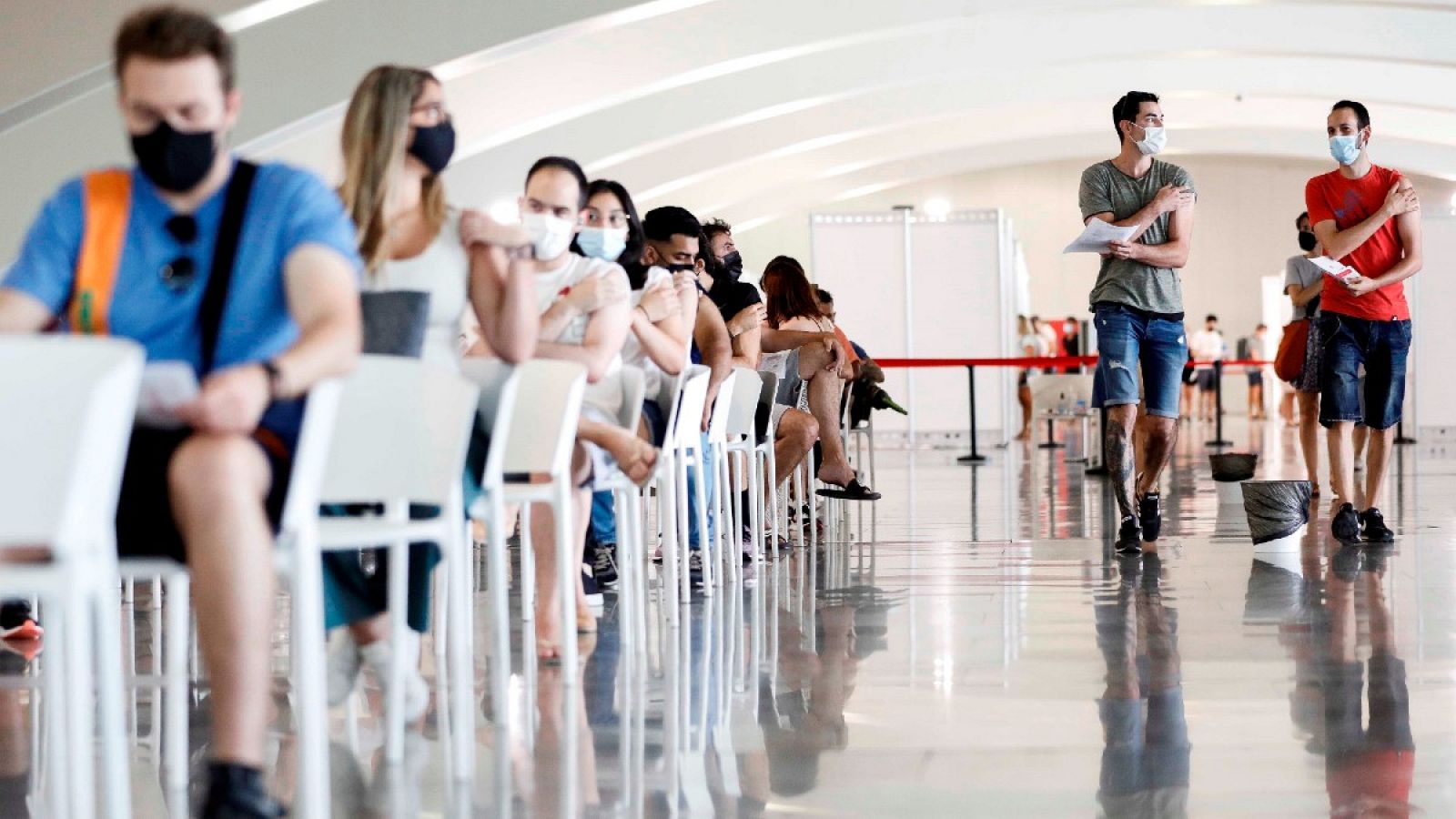 Varias personas esperan tras recibir la dosis de la vacuna en la Ciudad de las Artes y las Ciencias de Valencia