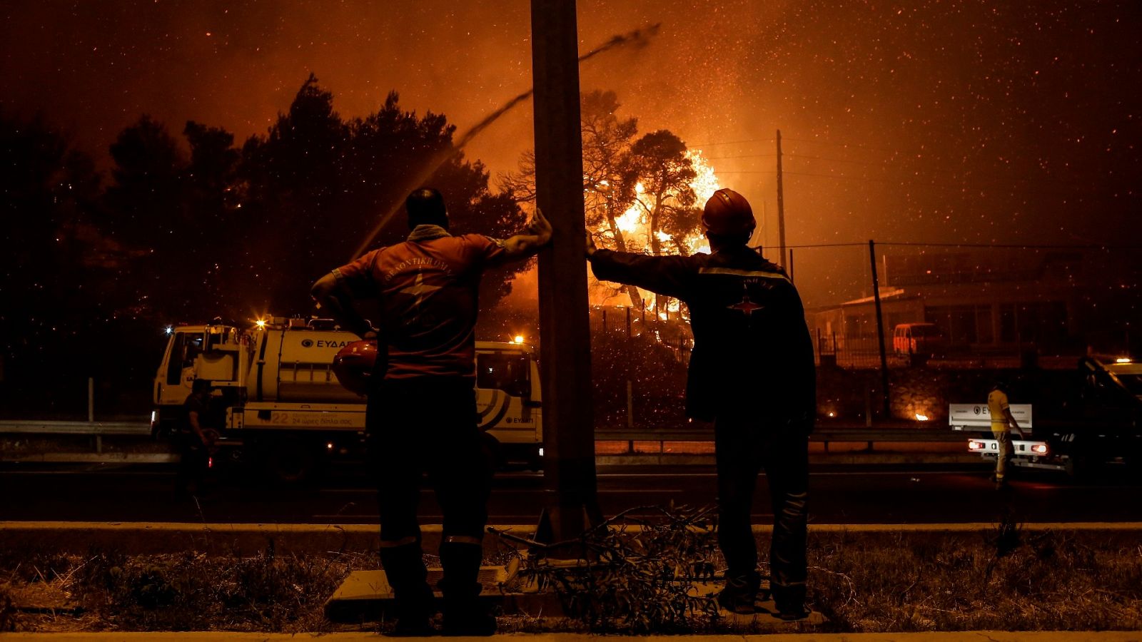 Bomberos voluntarios miran las llamas acercándose a una autopista en la zona de Afidnes, en Atenas (Grecia)