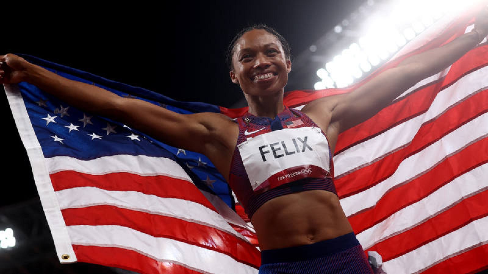 Allyson Felix, arropada con la bandera de Estados Unidos.