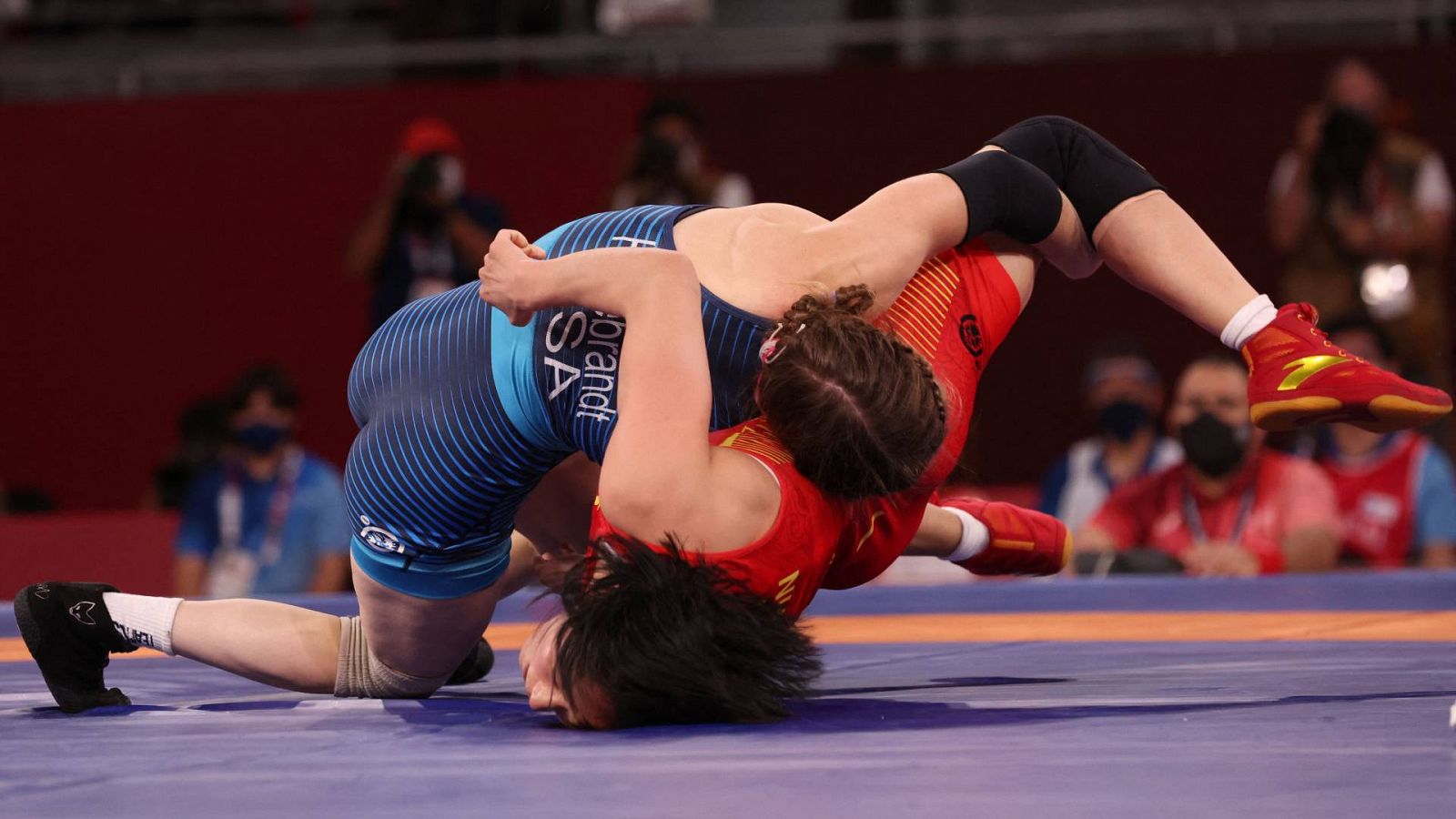 La estadounidense Sarah Ann Hildebrandt, de azul, voltea a la china Sun Yanan en la semifinal de lucha libre de menos de 50 kilos de Tokyo 2020