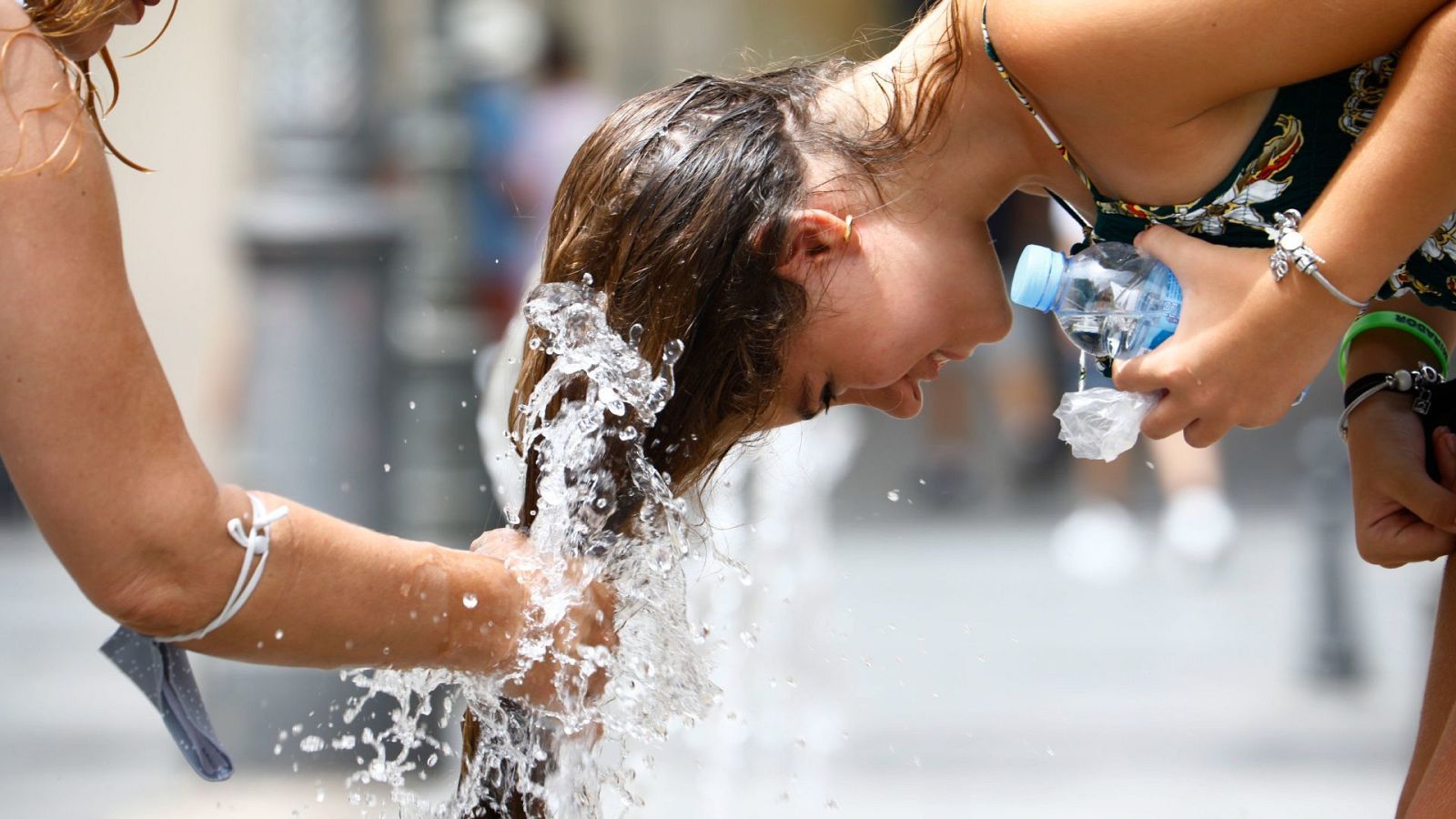 Una chica se refresca en una fuente del centro de Córdoba