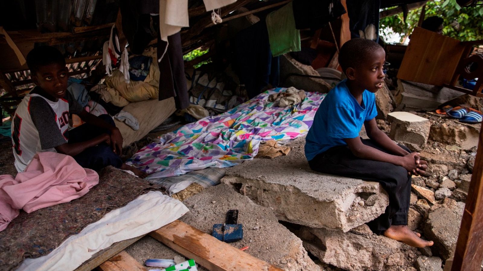 Niños permanecen protegidos en los restos de su hogar durante el paso de la tormenta Grace