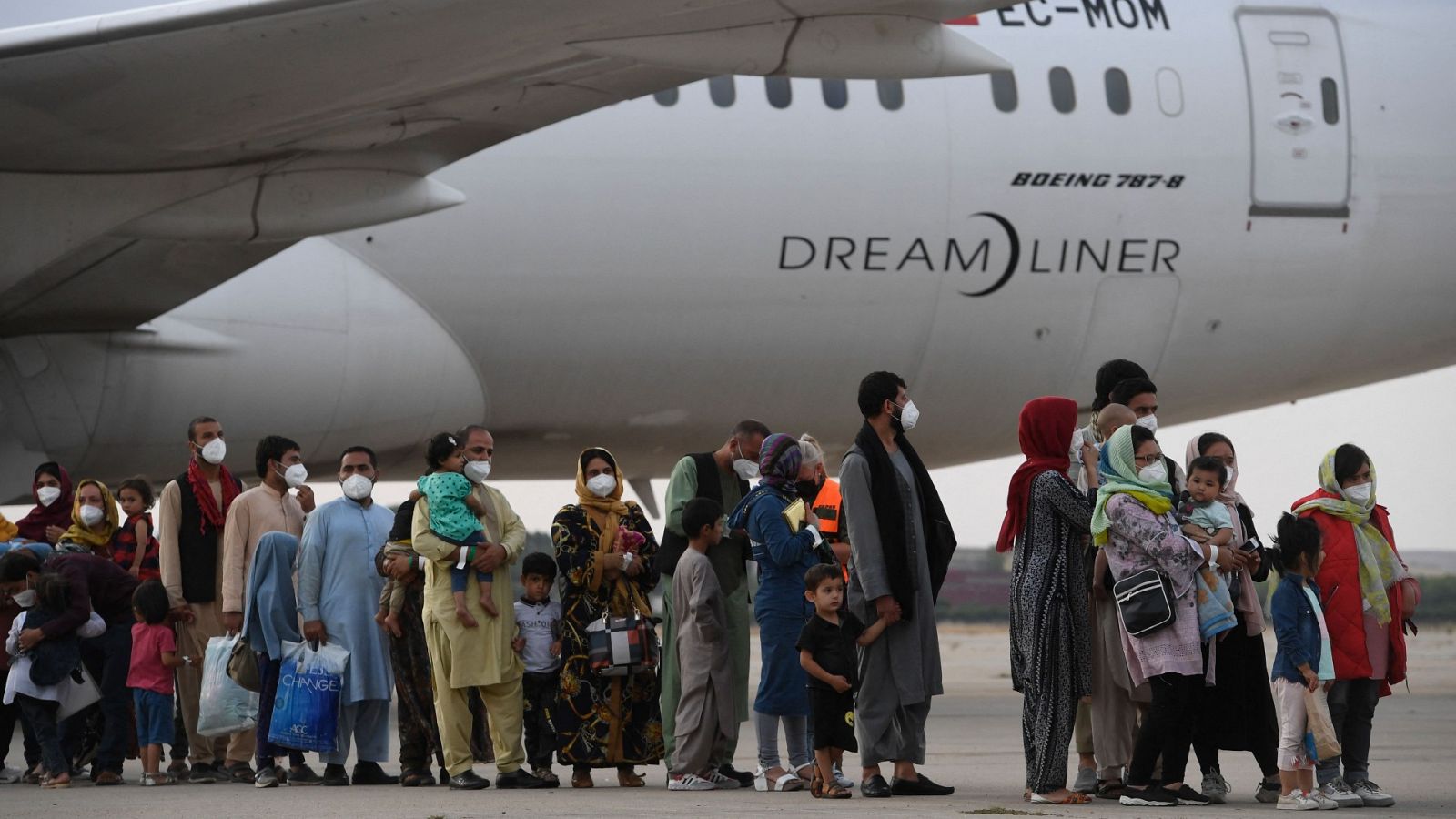Los refugiados hacen cola en la pista después de desembarcar de un vuelo de evacuación de Kabul