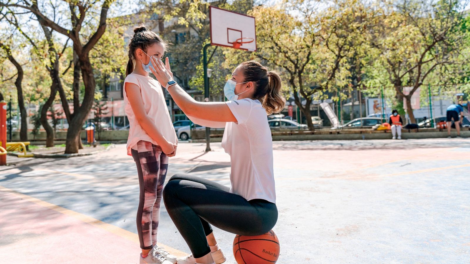 Una madre acompaña a su hija a clase de baloncesto en su centro escolar.