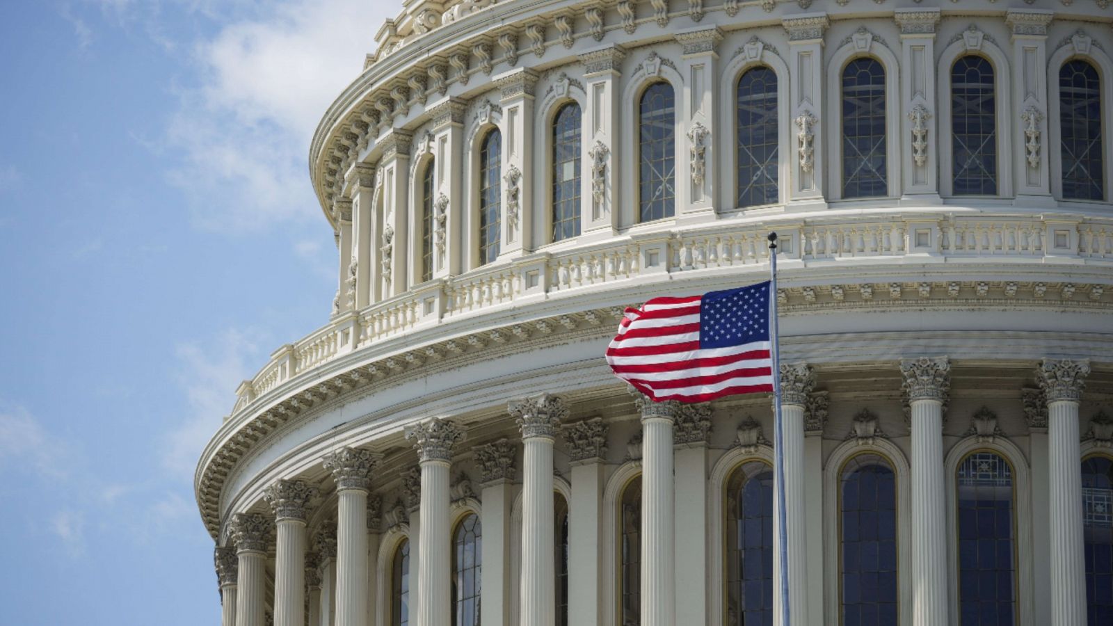 Imagen de una bandera estadounidense ondeando frente a la cúpula del Capitolio.