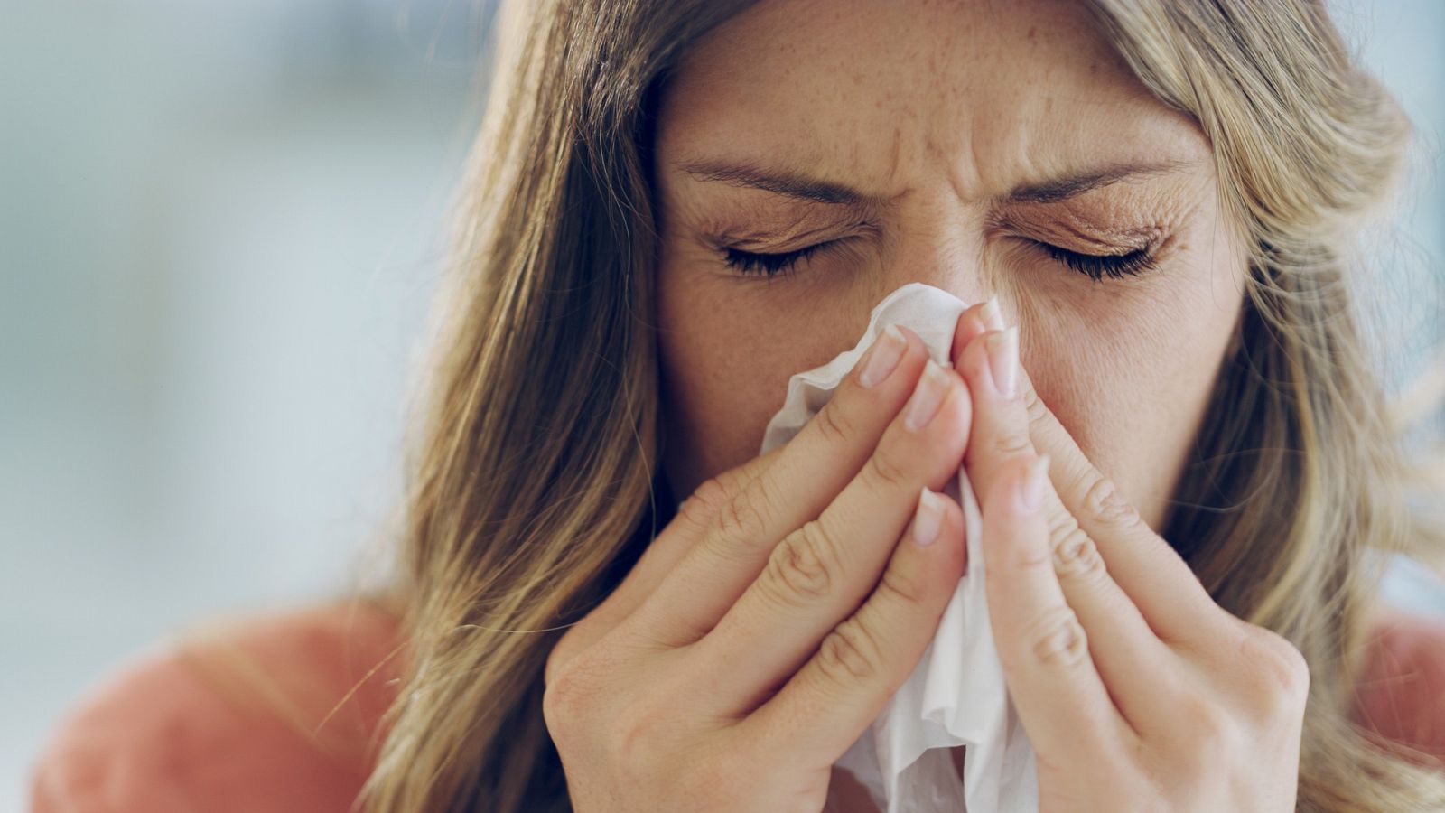 Una enferma de gripe se suena la nariz