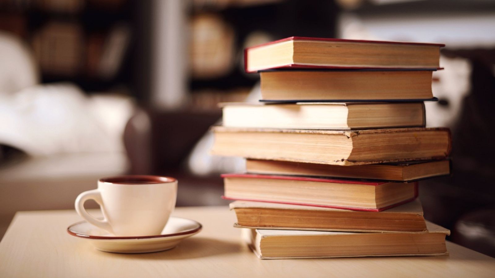 Una pila de libros junto a una taza de café