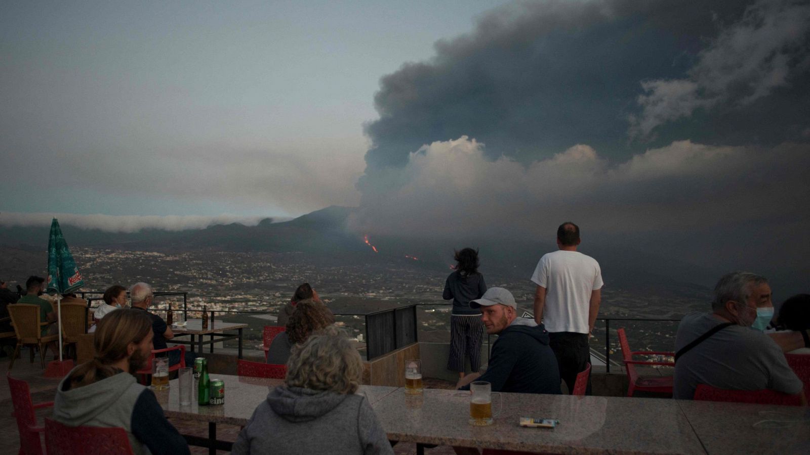 Varias personas observan desde Tijarafe la erupción del volcán de Cumbre Vieja, en la isla canaria de La Palma.