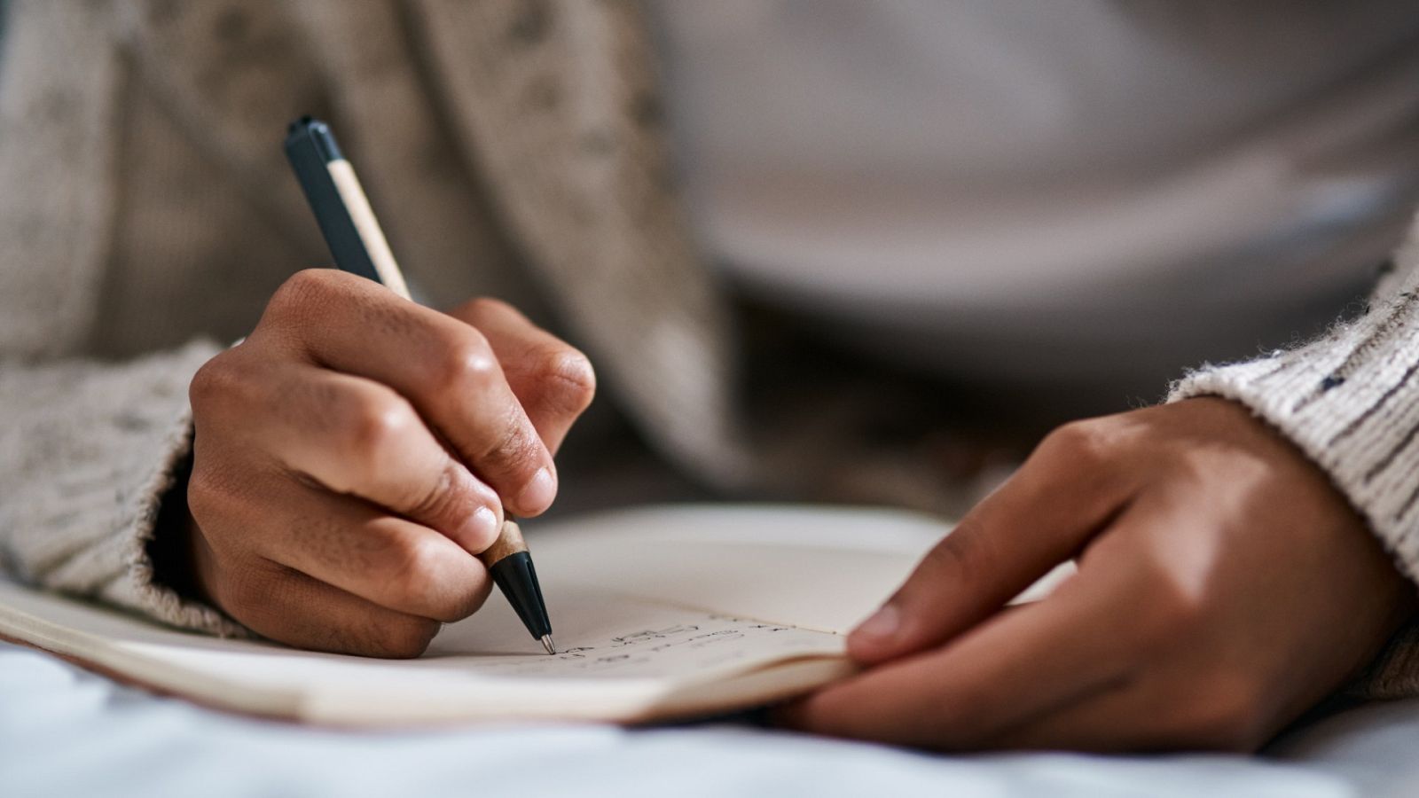 Detalle de una persona escribiendo en un cuaderno