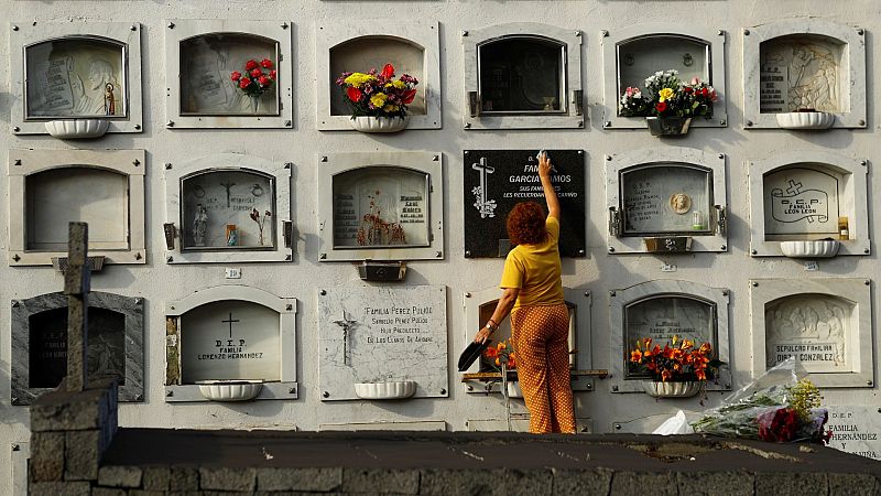 Una mujer limpia la ceniza del volcán en el cementerio de Los Llanos de Aridane