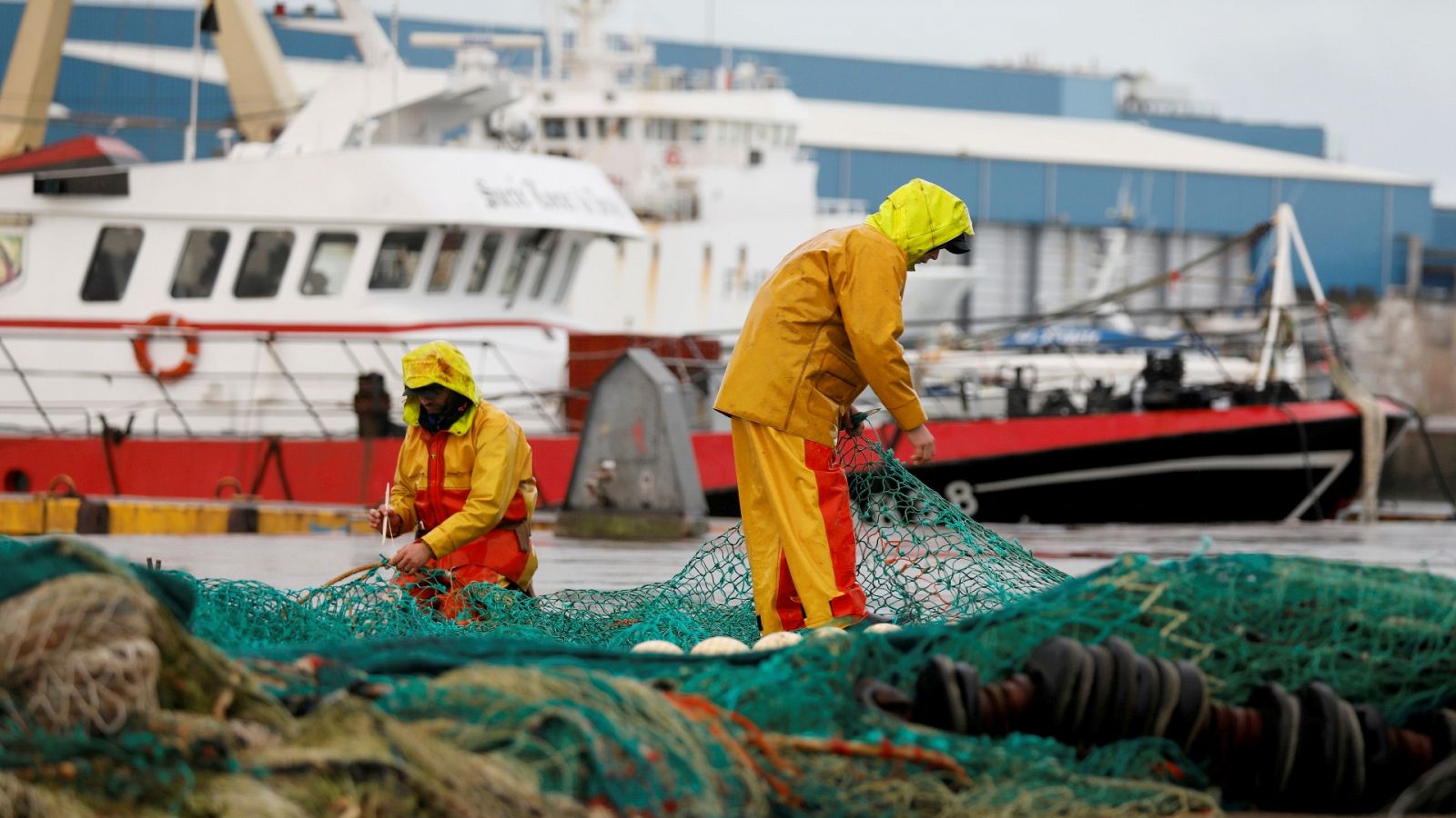 Un grupo de pescadores repara sus redes en un puerto