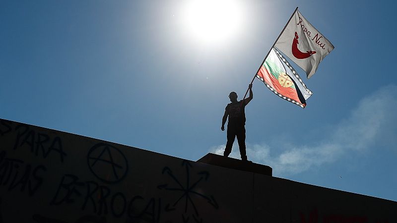 Un manifestante sostiene dos banderas indígenas